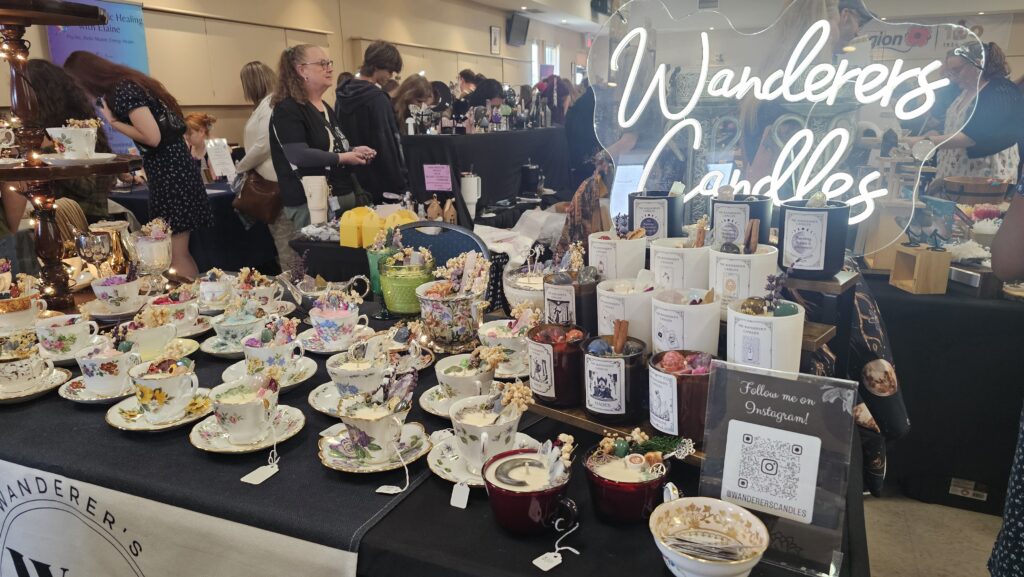 A picture of handmade candles by Wanderer's Candles. A table is set with crystal intention candles and tea cup candles.